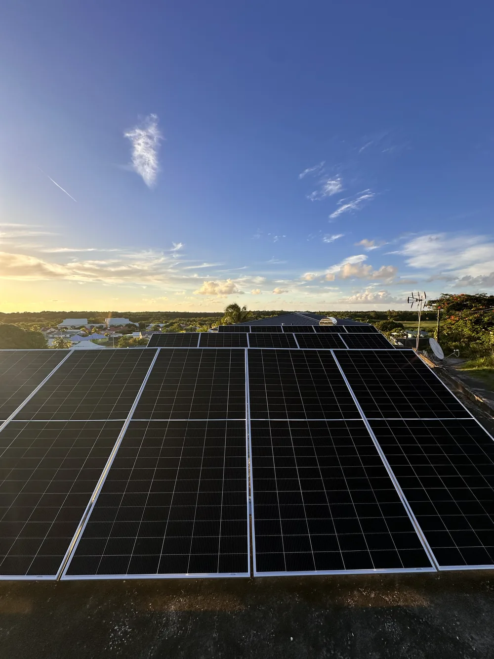 Installation solaire en toiture en Guadeloupe au coucher du soleil, panneaux photovoltaiques et vue sur la campagne